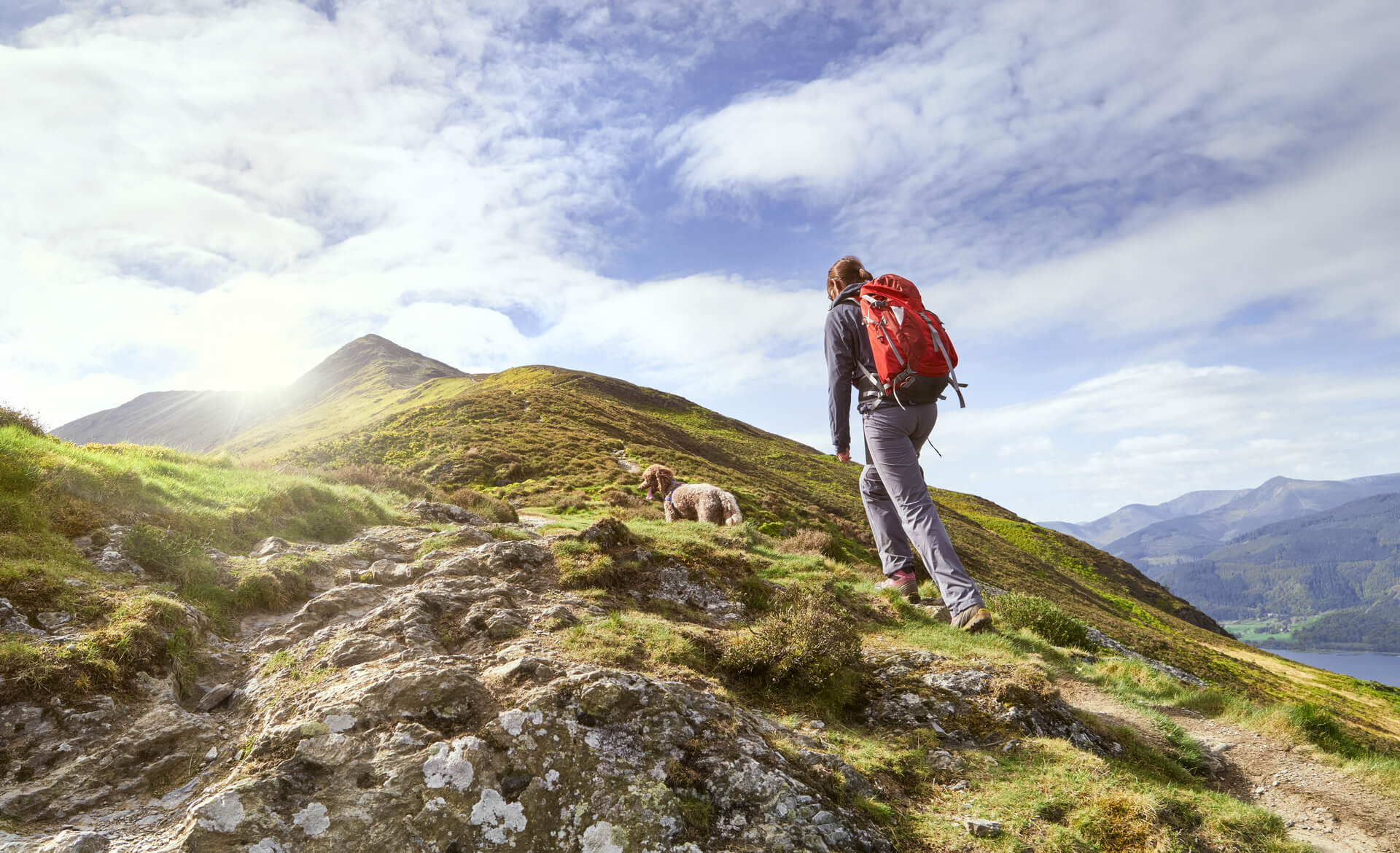 A woman hiking up a mountain with her dog